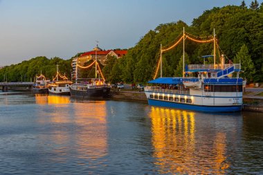 Turku, Finlandiya, 19 Temmuz 2022: Turku, Finlandiya 'da Aura nehri kıyısında demirleyen teknelerin gün batımı manzarası.