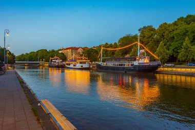 Turku, Finlandiya, 19 Temmuz 2022: Turku, Finlandiya 'da Aura nehri kıyısında demirleyen teknelerin gün batımı manzarası.