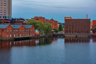 Tampere, Finlandiya, 21 Temmuz 2022: Tampere, Finlandiya 'da Tammerkoski kanalı ile birlikte tuğla binaların günbatımı manzarası.
