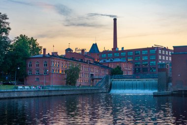 Tampere, Finlandiya, 21 Temmuz 2022: Tampere, Finlandiya 'da Tammerkoski kanalı ile birlikte tuğla binaların günbatımı manzarası.