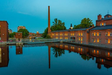 Tampere, Finlandiya, 21 Temmuz 2022: Tampere, Finlandiya 'da Tammerkoski kanalı ile birlikte tuğla binaların günbatımı manzarası.