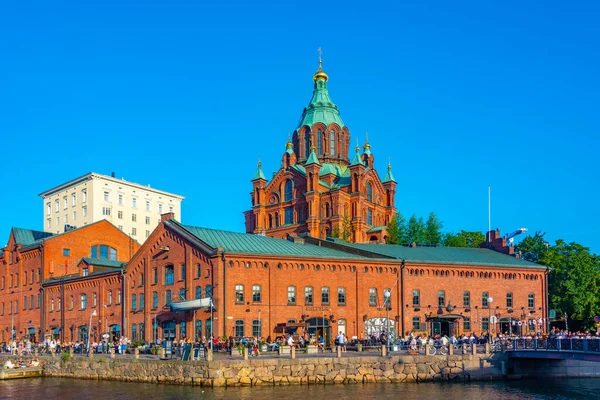 stock image Helsinki, Finland, July 20, 2022: Uspenski Cathedral rising above red brick buildings of former merchant port now transformed into public place in Helsinki, Finland .