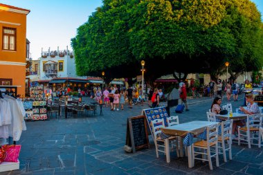 Rodos, Yunanistan, 27 Ağustos 2022: Yunan kenti Rodos 'ta bir turist caddesinin gün batımı manzarası.