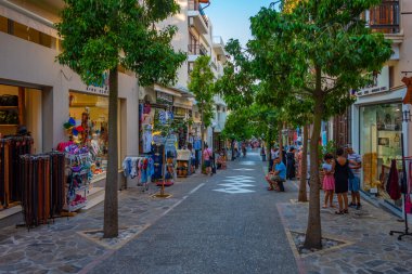 Agios Nikolaos, Yunanistan, 19 Ağustos 2022: Yunanistan 'ın Girit adasındaki Agios Nikolaos kasabasında turistik bir sokakta gezinen insanların günbatımı.