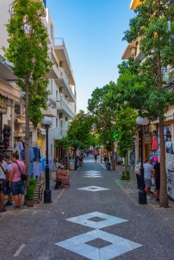 Agios Nikolaos, Yunanistan, 19 Ağustos 2022: Yunanistan 'ın Girit adasındaki Agios Nikolaos kasabasında turistik bir sokakta gezinen insanların günbatımı.