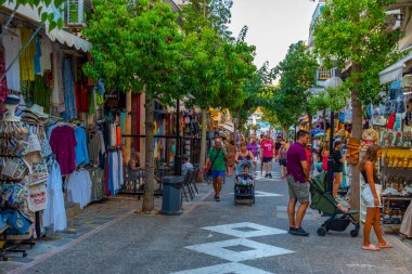 Agios Nikolaos, Yunanistan, 19 Ağustos 2022: Yunanistan 'ın Girit adasındaki Agios Nikolaos kasabasında turistik bir sokakta gezinen insanların günbatımı.