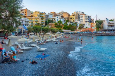 Agios Nikolaos, Yunanistan, 19 Ağustos 2022: Girit adasındaki Agios Nikolaos Yunan kasabasındaki Paralia Kitroplatia plajının gün batımı manzarası.