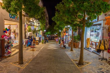 Agios Nikolaos, Yunanistan, 19 Ağustos 2022: Yunanistan 'ın Girit adasındaki Agios Nikolaos kasabasında turistik bir sokakta gezinen insanların günbatımı.