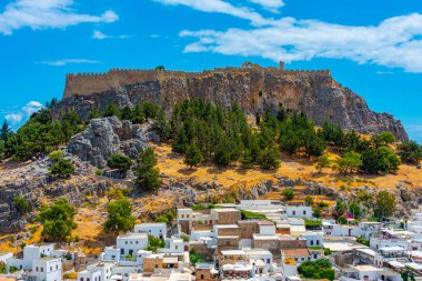 Lindos, Yunanistan, 25 Ağustos 2022: Yunanistan 'ın Rodos adasındaki geleneksel beyaz evlere bakan Lindos Akropolü.