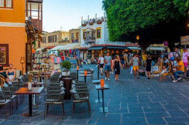 Rodos, Yunanistan, 27 Ağustos 2022: Yunan kenti Rodos 'ta bir turist caddesinin gün batımı manzarası.