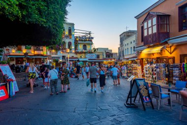Rodos, Yunanistan, 27 Ağustos 2022: Yunan kenti Rodos 'ta bir turist caddesinin gün batımı manzarası.