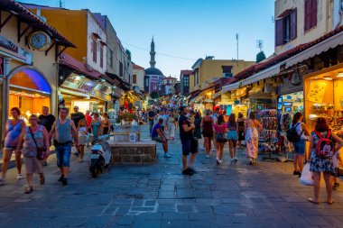 Rodos, Yunanistan, 27 Ağustos 2022: Yunanistan 'ın Girit adasındaki Rodos limanındaki Süleyman Camii' ne giden bir turist caddesinin gün batımı manzarası.