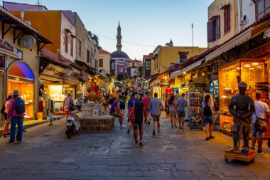 Rodos, Yunanistan, 27 Ağustos 2022: Yunanistan 'ın Girit adasındaki Rodos limanındaki Süleyman Camii' ne giden bir turist caddesinin gün batımı manzarası.