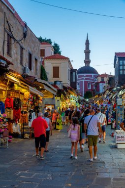 Rodos, Yunanistan, 27 Ağustos 2022: Yunanistan 'ın Girit adasındaki Rodos limanındaki Süleyman Camii' ne giden bir turist caddesinin gün batımı manzarası.