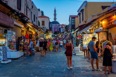 Rodos, Yunanistan, 27 Ağustos 2022: Yunanistan 'ın Girit adasındaki Rodos limanındaki Süleyman Camii' ne giden bir turist caddesinin gün batımı manzarası.