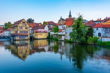 Bamberg, Almanya, 10 Ağustos 2022: Alman şehri Bamberg 'in Regnitz nehrine yansıyan gün batımı manzarası.