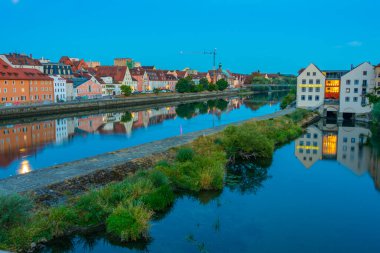 Regensburg, Almanya, 13 Ağustos 2022: Almanya 'nın Regensburg kentindeki Tuna Nehri' nin rıhtımındaki renkli evlerin gün doğumu manzarası.