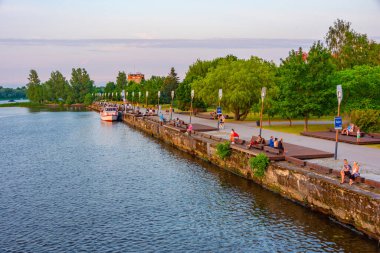 Parnu, Estonya, 1 Temmuz 2022: İnsanlar Estonya 'daki Parnu nehrinin nehir kıyısında günbatımının tadını çıkarıyorlar.