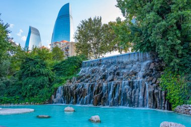 Azerbaycan, Bakü 'deki Selale Parkı' ndaki şelalenin arkasında alev kuleleri görülüyor.