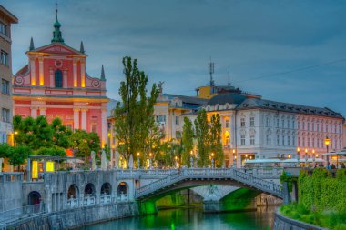 Slovenya 'nın Ljubljana kentindeki Ljubljanica nehrinin nehir kenarındaki Annunciation Kilisesi' nin gün batımı manzarası