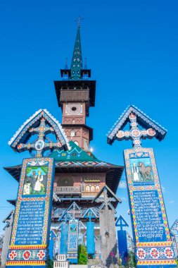Sapanta, Romania, August 11, 2023: Church of the Nativity of the Mother of God and decorated tombstones at the Merry cemetary in Romanian village Sapanta clipart
