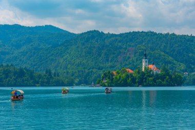 Bled, Slovenya, 20 Haziran 2023: Slovenya 'daki Bled Gölü' ndeki kiliseye turist getiren tekneler
