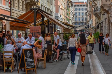 Trieste, İtalya, 22 Haziran 2023: İnsanlar İtalyan kenti Trieste 'nin merkezindeki tarihi bir sokakta geziniyorlar