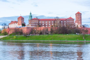 Polonya 'nın Krakow / Krakow kentindeki aydınlanmış Wawel şatosu gece boyunca Vistula / Wisla nehrine yansıdı.