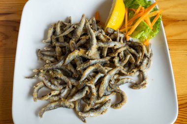 Kızarmış balık, patates kızartması, limon ve havuçla servis edilir.