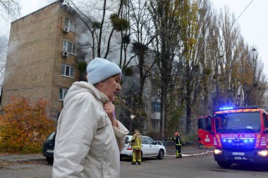 Bir kadın, Rusya 'nın Ukrayna, Kyiv, Ukrayna' ya 15 Kasım 2022 'de düzenlediği saldırıda Rus füze saldırısının vurduğu bir binada yangının yanından geçiyor.