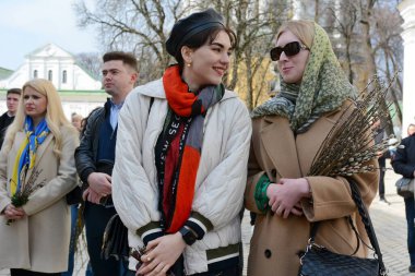 İnsanlar, Moskova Patrikliği 'nden Ukrayna Ortodoks Kilisesi, Kyiv' e 9 Nisan 2023 'te başarılı bir şekilde iade edilen Kyiv-Pechersk Lavra Rafinerisi' nin önünde düzenlenen Pazar ayini sırasında söğüt buketleri tutarlar..