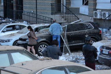 30 Mayıs 2023 'te Rusya-Ukrayna savaşı sırasında Ukrayna' nın başkenti Kyiv 'de meydana gelen gece insansız hava aracı saldırısı sonrasında insanlar hasar gören konut binasının yakınında bekliyorlar..