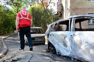 Kızıl Haç 'ın bir temsilcisi 30 Mayıs 2023' te Ukrayna 'nın başkenti Kyiv' de bir Rus insansız hava aracı patlaması sonucu yok olan araçların yanında yürüyor.