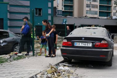 24 Haziran 2023 'te Ukrayna' nın başkenti Kyiv 'de Rusya' nın füze saldırıları sırasında hasar gören bir apartman binasının önündeki enkaz yığınlarına bakan insanlar görülüyor.