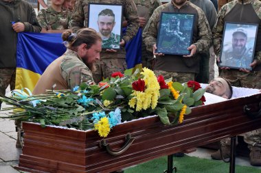 Bir asker, Kyiv 'deki Bağımsızlık Meydanı' nda veda ederken asker Yury Semenyuk 'un cesediyle birlikte tabutun yanına çiçek bırakıyor.