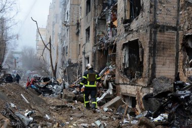 2 Ocak 2024 'te Kyiv' in merkezinde Rusya 'nın Ukrayna işgalinin arka planına karşı roket saldırısı sonucu yıkılan yüksek binaların yakınlarındaki bir itfaiyeci..