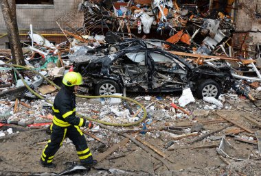 2 Ocak 2024 'te Kyiv' in merkezinde Rusya 'nın Ukrayna işgalinin arka planına karşı roket saldırısı sonucu yıkılan yüksek binaların yakınlarındaki bir itfaiyeci..