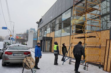 KYIV, UKRAINE - 20240103: Erkekler, 3 Ocak 2024 'te Ukrayna' nın başkenti Kyiv 'de yapılan bir Rus füze saldırısı sonrasında kırık camları tahta kontrplakla kaplıyorlar. 2 Ocak sabahı, Rus kuvvetleri Kyiv 'e büyük bir füze saldırısı düzenledi..