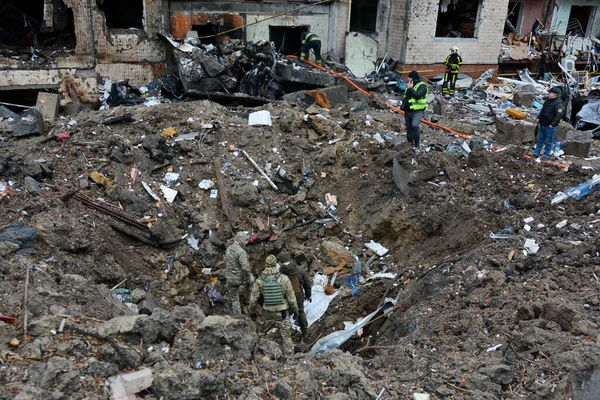 2 Ocak 2024 'te Ukrayna' nın başkenti Kyiv 'de Rus füze enkazı altında bir kraterin içinde askeri görevliler duruyor. 2 Ocak sabahı, Rus kuvvetleri Kyiv 'e büyük bir füze saldırısı düzenledi. Enkaz yıkıldı, ve binalar yandı.