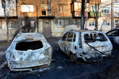 Yerel halk, 21 Mart 2024 'te Kyiv' de meydana gelen saldırıdan sonra roket enkazının düştüğü yerin yakınlarında yanan arabaları inceliyor..
