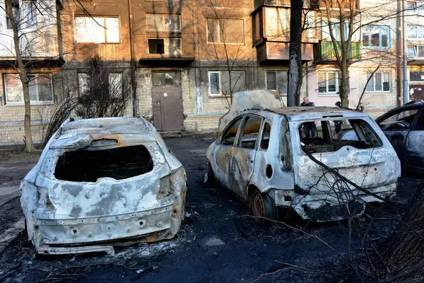Yerel halk, 21 Mart 2024 'te Kyiv' de meydana gelen saldırıdan sonra roket enkazının düştüğü yerin yakınlarında yanan arabaları inceliyor..
