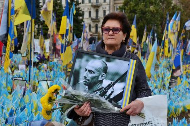 Bir kadın, Ukrayna 'nın başkenti Kyiv' de 1 Ekim 2024 'te ölen Ukraynalı askerlerin derme çatma bir anıtının yanında akrabasının portresini tutuyor..