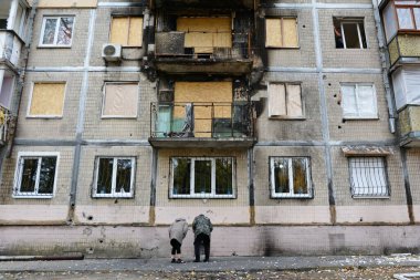 30 Ekim 2024 'te Ukrayna' nın başkenti Kyiv 'de meydana gelen Rus insansız hava aracı saldırısının ardından hasar görmüş bir yerleşim yerinin yakınındaki yerel halk yangın izleri taşıyor..