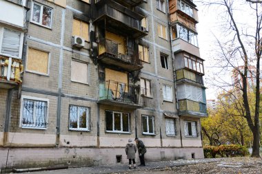 30 Ekim 2024 'te Ukrayna' nın başkenti Kyiv 'de meydana gelen Rus insansız hava aracı saldırısının ardından hasar görmüş bir yerleşim yerinin yakınındaki yerel halk yangın izleri taşıyor.. 