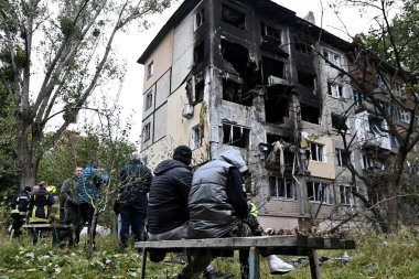 28 Eylül 2025 'te Ukrayna' nın başkenti Kyiv 'de meydana gelen bir Rus saldırısında hasar gören bir apartmanın bahçesindeki bankta oturan insanlar görülüyor.
