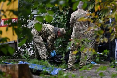 Askeri idare ve polis temsilcileri, 28 Eylül 2025 'te Ukrayna' nın başkenti Kyiv 'de meydana gelen bir Rus saldırısında yaralanan bir apartmanın avlusunda ölü bir kızın cesedini siyah bir çantaya sardılar.