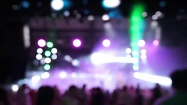 İnsanlar gece kulübünde konser veriyor. Arkaplan bulanık ışıklar.