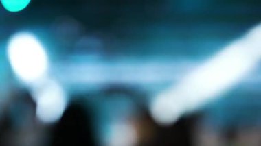 İnsanlar gece kulübünde konser veriyor. Arkaplan bulanık ışıklar.