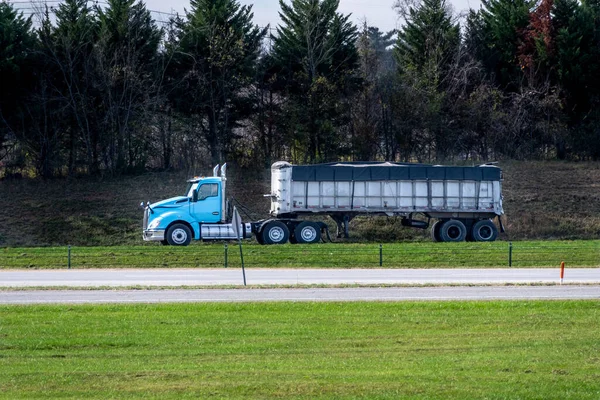 Horizontal shot of a light blue truck with trailer and copy space.  Trailer is covered with a tarp.