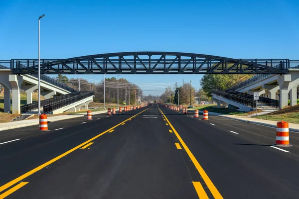 歩道橋の下には 新しく塗装されたストライプとオレンジのトラフィックバレルが新しく黒い上の道路に見られます — ストック写真